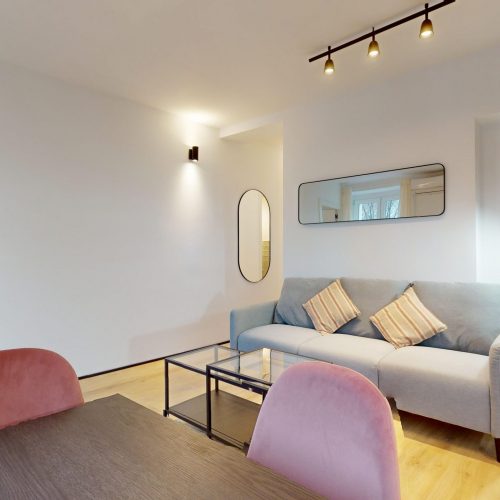 Salón moderno de apartamento con predominio de blanco y tonos crema; demuestra cómo la inversión en reforma de inmuebles transforma espacios y aumenta el valor de la propiedad.